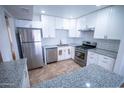Modern kitchen with stainless steel appliances, granite countertops, white cabinets, and stylish tile backsplash at 5217 N 18Th Dr, Phoenix, AZ 85015