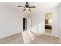 Bright bedroom featuring neutral carpet, ceiling fan, and view to bathroom at 5329 E Harmony Ave, Mesa, AZ 85206