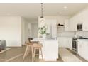 Stylish kitchen featuring a center island with seating, sleek white cabinets, and modern lighting at 7420 S 76Th Ln, Laveen, AZ 85339