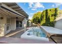 Private backyard featuring a covered patio, mature trees, brick pavers, and a relaxing hot tub at 8405 E San Pedro Dr, Scottsdale, AZ 85258