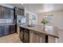 Kitchen island featuring a stainless steel sink and appliances, granite countertops, and dark cabinets at 900 E Harrison St, Chandler, AZ 85225
