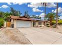 Exterior view of a single-story home with a long concrete driveway and two-car garage at 134 E Le Marche Ave, Phoenix, AZ 85022
