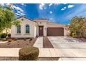 Inviting single-story home featuring a two-car garage and beautiful landscaping under a bright sky at 14549 W Corrine Dr, Surprise, AZ 85379