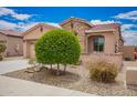 Single story home boasting well manicured landscaping including a round shrub, river rock, and a red tile roof at 17907 W Cedarwood Ln, Goodyear, AZ 85338