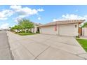 Three-car garage with a large concrete driveway and walkway lined with trees at 3440 E Topeka Dr, Phoenix, AZ 85050