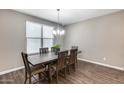 Cozy dining room with wood floors, a contemporary chandelier, and a view of the backyard at 35773 N Loemann Dr, San Tan Valley, AZ 85143
