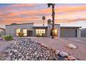 Inviting exterior view of a single-story home with desert landscaping and a palm tree at sunset at 5119 E Shaw Butte Dr, Scottsdale, AZ 85254