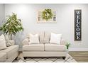 Inviting living room featuring a comfortable couch with pillows and a decorative wreath accenting the wall at 10617 W Daley Ln, Peoria, AZ 85383