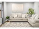 Cozy living area featuring a comfortable sofa with pillows, a decorative rug, and a charming potted plant at 10617 W Daley Ln, Peoria, AZ 85383
