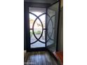 View of the custom iron front door and screen door with detailed circular design and wood-look tile flooring at 10738 W Rowel Rd, Peoria, AZ 85383