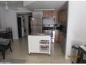 Open kitchen with stainless steel appliances, wooden cabinets, and functional rolling island at 12221 W Bell Rd # 209, Surprise, AZ 85378