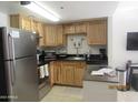 Well-lit kitchen features stainless steel appliances, wood cabinets, and black countertops at 12221 W Bell Rd # 209, Surprise, AZ 85378
