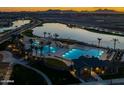 Stunning aerial view showcasing resort-style community pools, lush landscaping, and serene lake views at sunset at 22980 E Raven Dr, Queen Creek, AZ 85142