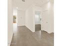 Bright interior hallway featuring ceramic tile flooring and white walls with a view of the backyard at 37125 W Prado St, Maricopa, AZ 85138