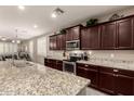 Modern kitchen with granite countertops, stainless steel appliances, and dark wood cabinetry at 41342 W Elm Dr, Maricopa, AZ 85138