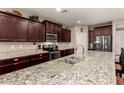Spacious kitchen featuring stainless steel appliances, granite countertops, and dark wood cabinets at 41342 W Elm Dr, Maricopa, AZ 85138