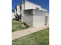 Angle view of the townhome's stucco siding and cozy, fenced-in front patio, surrounded by a green lawn at 5212 N 42Nd Ln, Phoenix, AZ 85019