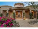 An arched entrance with stone accents and lush flowers welcomes you to the Southwest home at 10092 E Troon North Dr, Scottsdale, AZ 85262