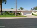 Inviting home featuring a well-maintained lawn, complemented by mature trees, and a convenient two-car garage at 10229 W Bolivar Dr, Sun City, AZ 85351