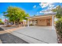 Charming home featuring a spacious covered parking area, desert landscaping, and a mature shade tree at 155 E Rodeo Rd # 64, Casa Grande, AZ 85122