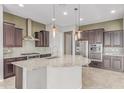 Gourmet kitchen features a large island with granite countertops, stainless steel appliances, and stylish pendant lighting at 27537 W Yukon Dr, Buckeye, AZ 85396