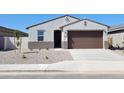Charming single-story home featuring a brown two car garage and low maintenance desert landscaping at 37139 W Prado St, Maricopa, AZ 85138