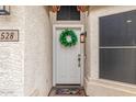 Charming front entrance with a white door, a wreath, a decorative light fixture, and a colorful welcome mat at 528 E Kyle Ct, Gilbert, AZ 85296