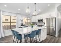 Bright kitchen featuring white cabinets, stainless steel appliances, a marble island with seating, and modern pendant lights at 528 E Kyle Ct, Gilbert, AZ 85296