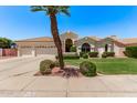 Inviting home featuring lush landscaping, a three-car garage, and a well-maintained lawn at 7648 W Mauna Loa Ln, Peoria, AZ 85381