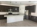 Modern kitchen with dark cabinetry, stainless steel appliances, and a large center island at 1081 E Armstrong Way, Chandler, AZ 85286