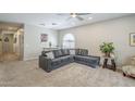 Inviting living room featuring neutral carpet, a ceiling fan, and a comfortable gray sectional couch at 15848 W Calavar Rd, Surprise, AZ 85379