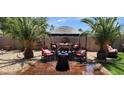 Inviting backyard patio with comfortable seating, shade umbrella, and lush palm trees creating a private retreat at 18177 W Tasha Dr, Surprise, AZ 85388
