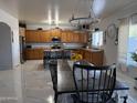 Open-concept kitchen and dining area with wood cabinets, stainless steel appliances, island seating, and modern lighting at 22966 W Hopi St, Buckeye, AZ 85326