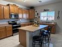 Well-lit kitchen featuring wood cabinets, stainless steel appliances, an island with bar seating, and marble floors at 22966 W Hopi St, Buckeye, AZ 85326