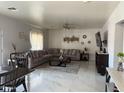 Spacious living room with marble floors, a large sectional sofa, and a modern ceiling fan at 22966 W Hopi St, Buckeye, AZ 85326