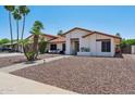 Inviting single-story home with mature palm trees, desert landscaping, and a cozy front patio at 5415 E Juniper Ave, Scottsdale, AZ 85254