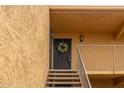 Second floor tan condo building with a floral wreath hanging on the front door near exterior sconce lights at 8500 E Indian School Rd # 233, Scottsdale, AZ 85251