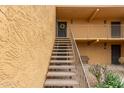 Staircase leading to tan second floor units in a condo building with sconce lights and bench at 8500 E Indian School Rd # 233, Scottsdale, AZ 85251