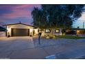 Charming home featuring a well-manicured front yard, dark garage door, updated lighting, and healthy trees at 8728 E Monte Vista Rd, Scottsdale, AZ 85257