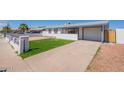 Inviting single-story home with a well-kept lawn, driveway, and white picket fence at 8802 W Monterey Way, Phoenix, AZ 85037