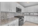 Bright kitchen featuring granite countertops, white cabinetry, and stainless steel appliances at 10305 E Plata Ave, Mesa, AZ 85212