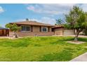 Attractive one-story brick house with lush green lawn, mature trees, and an attached garage at 1062 E Watson Dr, Tempe, AZ 85283