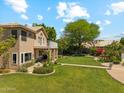 The back of this home features a spacious yard with a balcony, lush lawn and landscaping, and mature trees at 14655 S 25Th Way, Phoenix, AZ 85048
