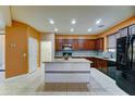 Open kitchen with dark wood cabinets, tiled backsplash, and a tiled kitchen island at 23773 W Hammond Ln, Buckeye, AZ 85326