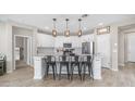 Spacious kitchen featuring an island with seating, modern lighting, white cabinets, and stainless steel appliances at 2822 E Hidalgo Ave, Phoenix, AZ 85040