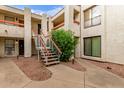 Exterior view of the building with white stairs and orange railings and landscaped common areas at 3119 W Cochise Dr # 111, Phoenix, AZ 85051