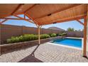 Beautiful backyard oasis with a covered patio, sparkling pool, and lush landscaping for relaxation at 42213 W Santa Fe St, Maricopa, AZ 85138