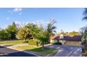 Beautiful single-level home with a well-manicured lawn, mature trees, and a circular driveway leading to a garage at 645 S Esquire Way, Mesa, AZ 85202