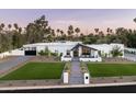 Eye-level view of a modern white home boasting palm trees, manicured lawn, and a stylish walkway to the entrance at 9733 E Clinton St, Scottsdale, AZ 85260
