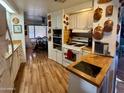Well-equipped kitchen with white cabinetry, gas range, and hardwood floors at 120 N Val Vista Dr # 151, Mesa, AZ 85213